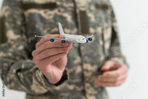 Military Technical Service, Air Force Concept. Hands of a man in uniform holding a silver toy airplane. A middle-aged adult man in a green camouflage uniform. Indoors. Selective Focus. Low key