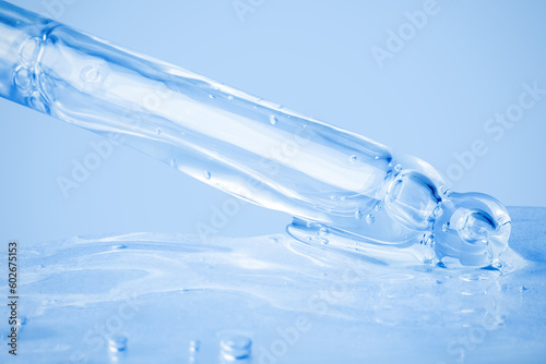 Transparent cosmetic gel flowing from the dropper and smeared on the background. On a blue background. Hyaluronic acid, toner, toner, gel, cream. Cosmetics.