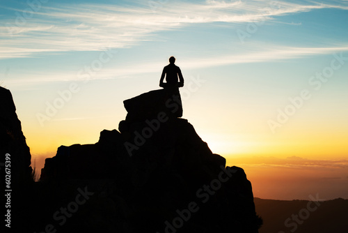 Silhouette Of Man Sitting On Top Of Mountain At Sunset