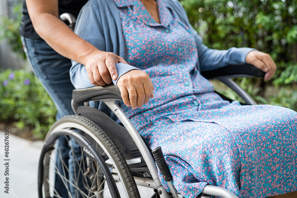 Obraz premium Caregiver help and care Asian senior woman patient sitting on wheelchair to ramp in nursing hospital, healthy strong medical concept.