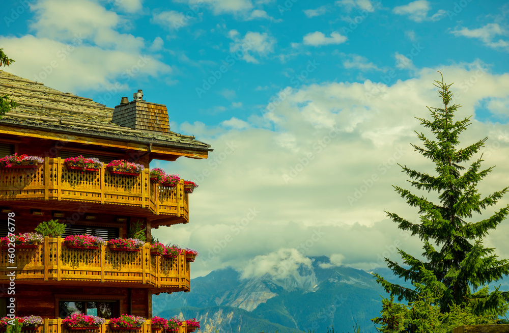 Fototapeta premium Wood Building with Balcony and Flower and Sunlight with Mountain in Crans Montana, valais in Switzerland.