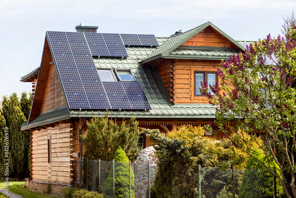 Solar panels on Roof of Old Wooden House in Countryside. Mansard Rooftop with Skylight Windows and Solar Panel System.