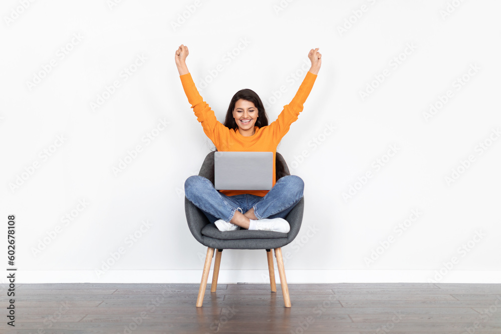 Emotional indian woman using laptop, raising hands up Emotional indian woman using laptop, raising hands up