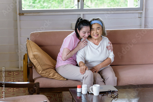 Asian young woman take care and  support with hug, that make feel good and smile older mother in living room. family concept photo