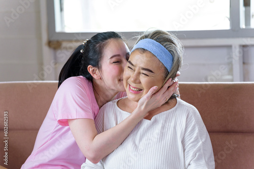 Asian young woman take care and  support with kiss, that make feel good and smile older mother in living room. family concept