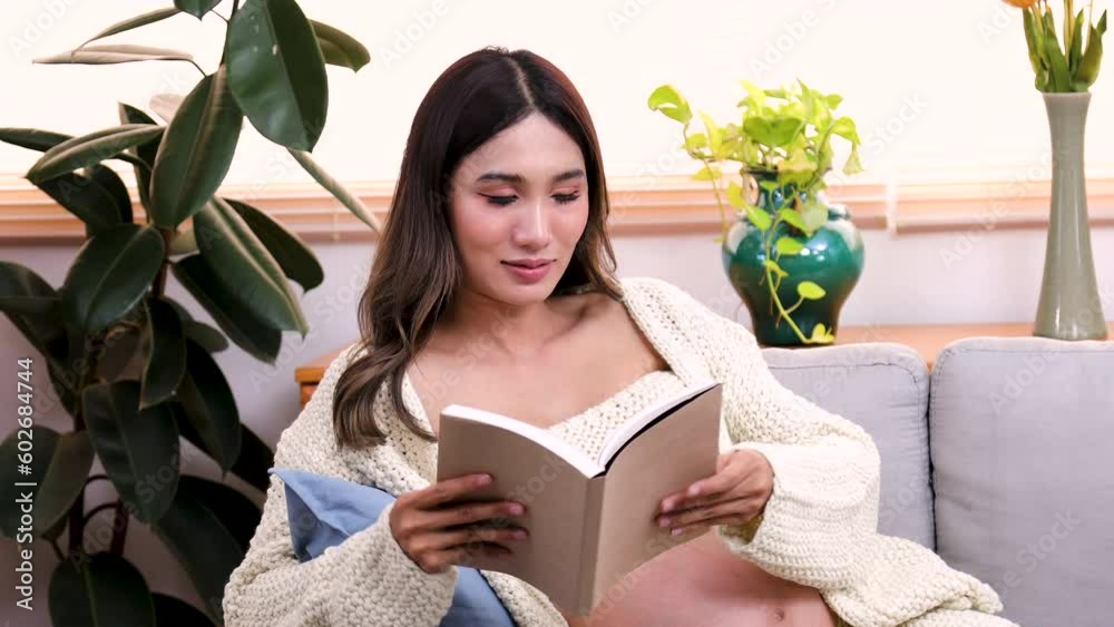Asian pregnant woman reading book lying down on sofa in living room at home, happy belly mother picks up favorite book for her relaxation time, newly pregnancy learning lifestyle to first givebirth Asian pregnant woman reading book lying down on sofa in living room at home, happy belly mother picks up favorite book for her relaxation time, newly pregnancy learning lifestyle to first givebirth