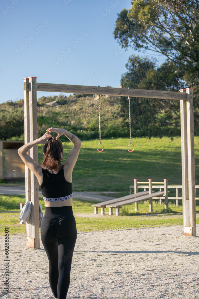 Young woman preparing for her workout at an outdoor calisthenics park 