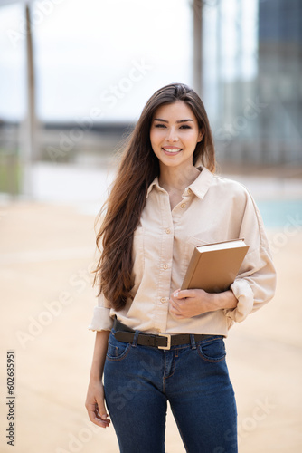 Positive pretty young asian lady student or teacher in casual with books ready for lesson
