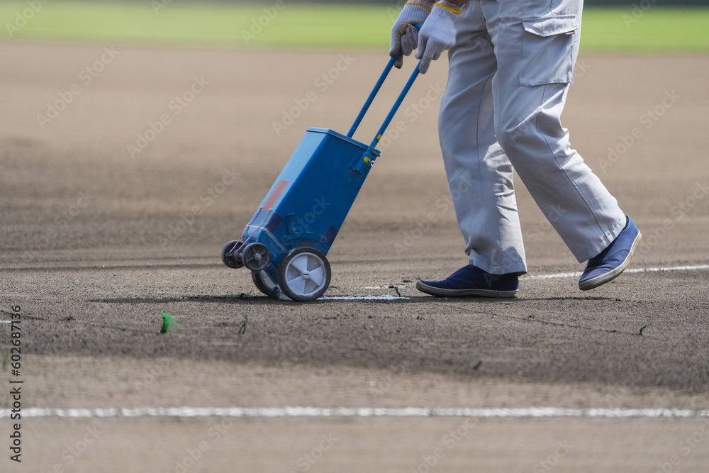 Obraz premium 野球の試合前のグランドで白線を引く整備員