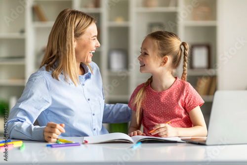 Mother And Cute Little Daughter Having Fun While Making School Homework Together
