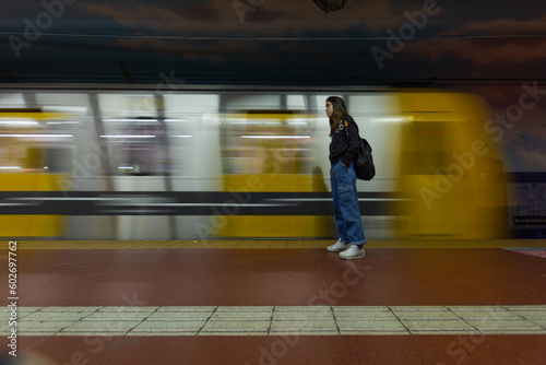 Young woman standing still waiting for moving subway train, whole body