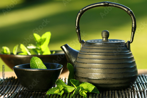 Fototapete Black iron asian teapot with sprigs of mint for tea