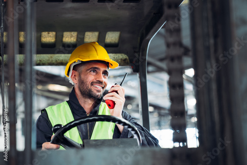 Industrial worker driving a forklift in the factory. Engineer is working and maintaining in the warehouse.