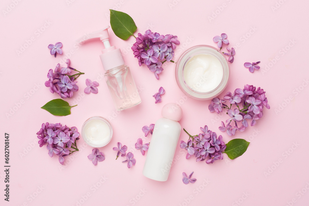 Composition with cosmetic bottles and flowers on color background, top view Composition with cosmetic bottles and flowers on color background, top view