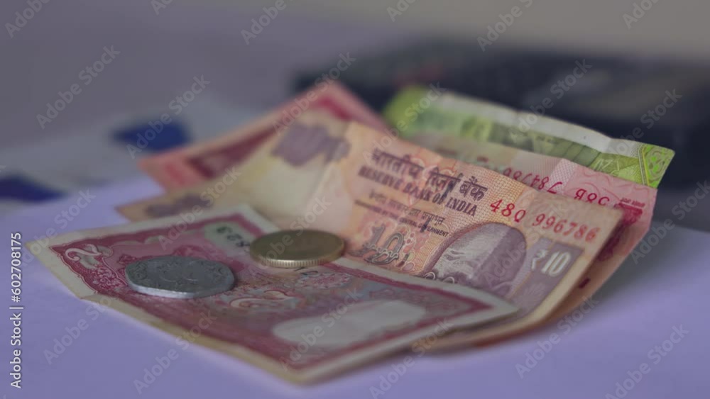 Closeup of Indian rupee coins falling over currency notes on a table Closeup of Indian rupee coins falling over currency notes on a table