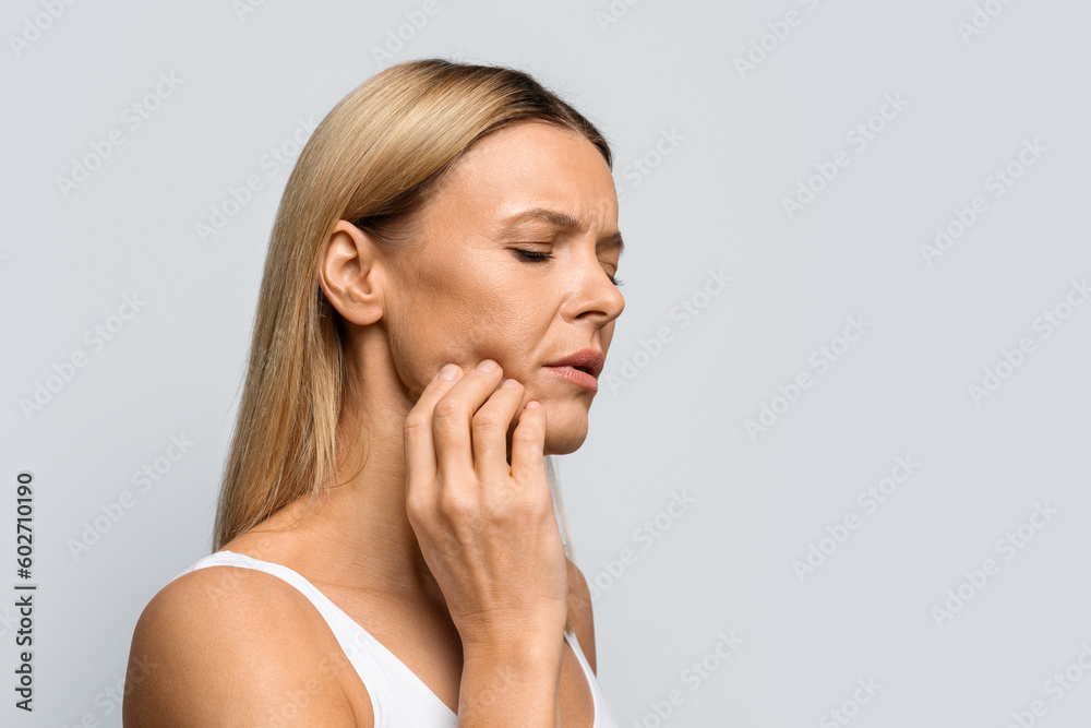 Middle aged woman in pain touching her cheek, copy space Middle aged woman in pain touching her cheek, copy space