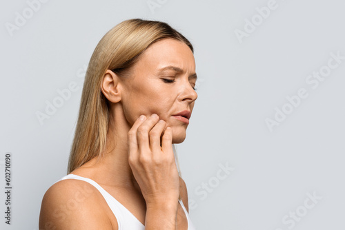 Middle aged woman in pain touching her cheek, copy space