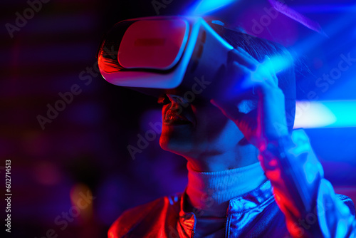 trendy woman in virtual reality goggles on dark background