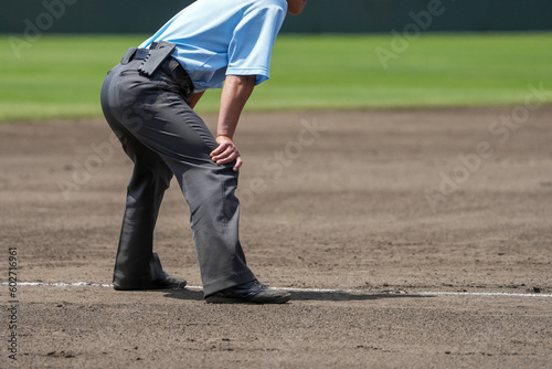 野球の試合中にピッチャーの投球とバッターの打球に対して身構える塁審