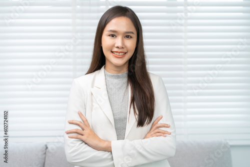 Smiling positive, attractive asian young woman wearing suit, standing with arms crossed at office portrait elegant person long brunette hair, feeling happy looking camera, isolated on white background