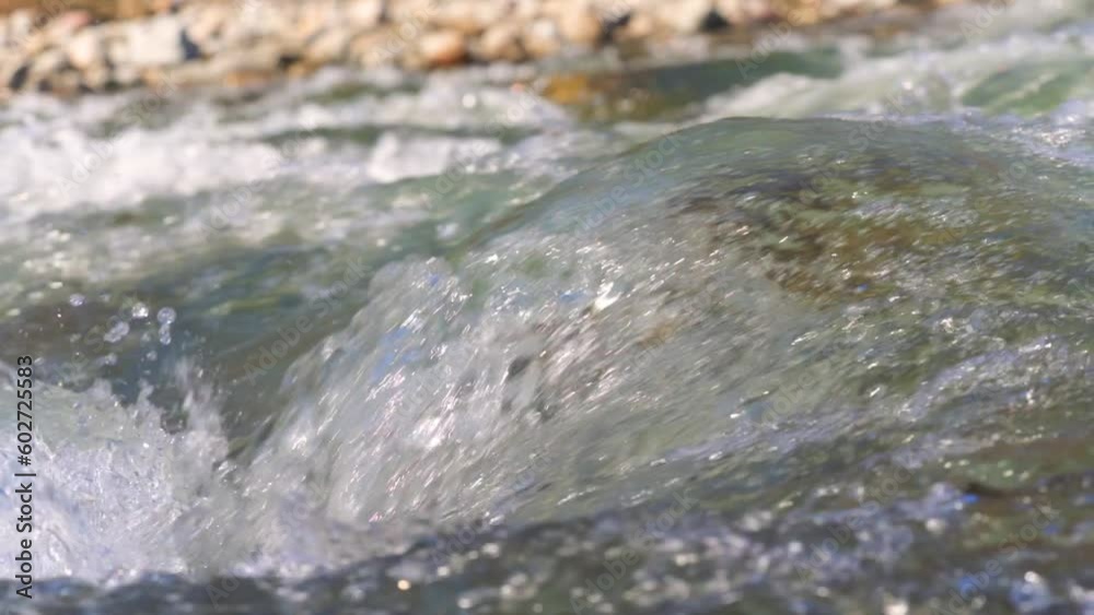 Water flowing in spring river over small rock, slow motion video Water flowing in spring river over small rock, slow motion video