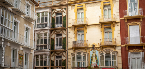 Details of typical facades of Cartagena, Murcia, Spain, of different colors and metal balconies and a mosaic of tiles with a Christian virgin