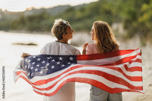 Two Women With US National Flag Enjoying Day On The Beach