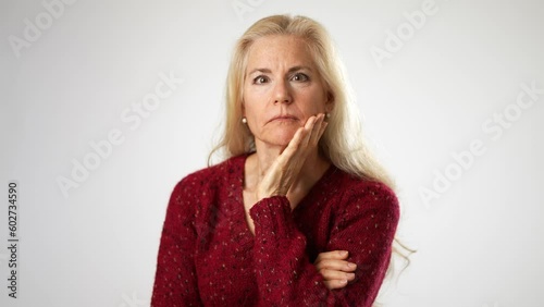 Portrait of attractive mature woman listen to secret with hand to ear, expressing doubts, unsure of heard information, suffering hearing problems at older age. Studio shot on white background