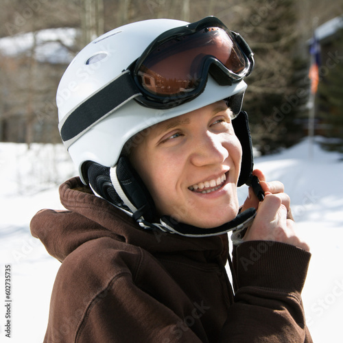 Caucasian male teenager fastening helmet.