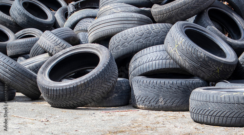 Garbage from a pile of black old car tires. Environmental pollution. Ecological problems. Old car tires thrown into an industrial landfill for recycling. Reuse of worn rubber tires.