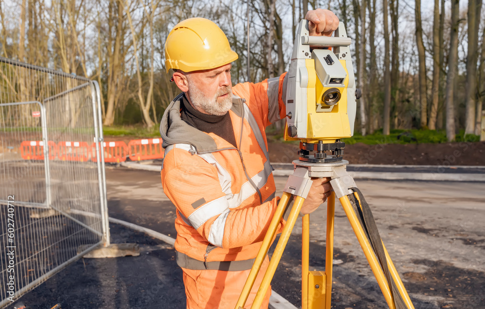 Site engineer setting his instrument during roadworks. Builder installing total positioning station tachymeter on construction site for new road setting out Site engineer setting his instrument during roadworks. Builder installing total positioning station tachymeter on construction site for new road setting out