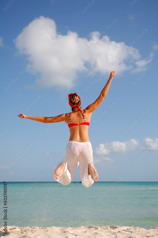 Woman in red and white jumping on the beach Woman in red and white jumping on the beach