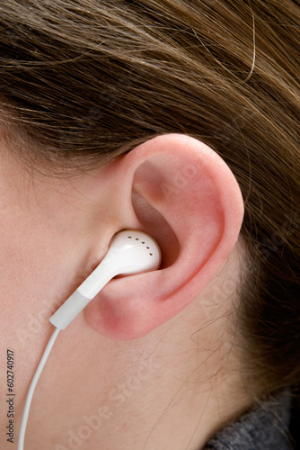 Young woman wearing white portable audio earphones.