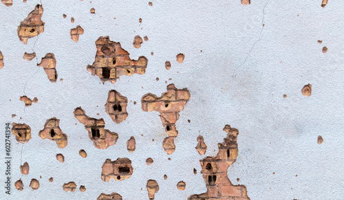The wall of a building battered by rocket fragments in a war zone. Shelled wall. Facade of a bombed-out building. Armed conflict in Ukraine. Damage to the house as a result of artillery shelling.
