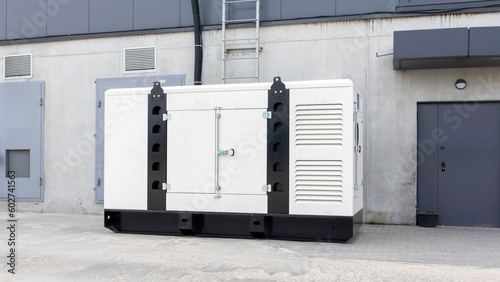 White auxiliary diesel generator for emergency power supply. Industrial generator connected to the control panel by a cable wire. Backup power supply of the generator.