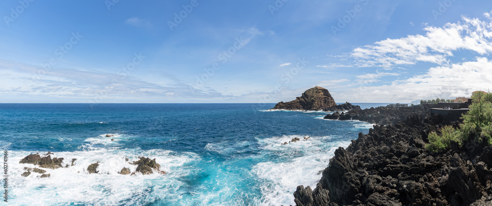 Panoramic view of the natural pools on village of Porto Moniz, formed by volcanic rocks, islet of Mole in the background, coast of the Madeira island, Portugal