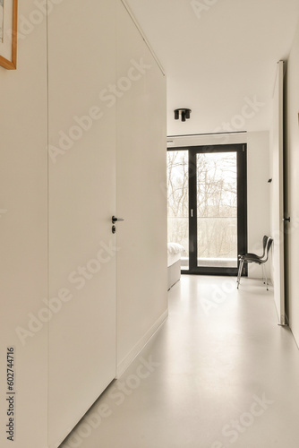 a long hallway with white walls and black trim on the doors, leading you to an open space where there is no one person