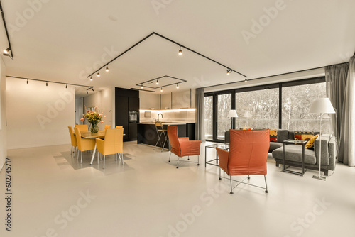 a living room with orange chairs and an open kitchen area in the photo is taken from the dining area to the right