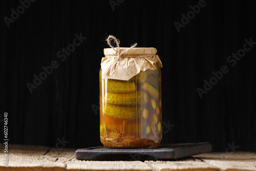 Pickled cucumbers in a jar on a dark background close-up, copy space.