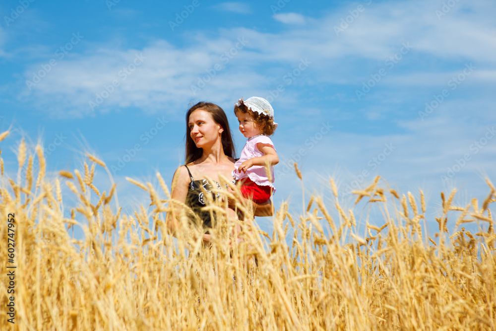 Mother holding daughter in hands, standing in a wheat field Mother holding daughter in hands, standing in a wheat field