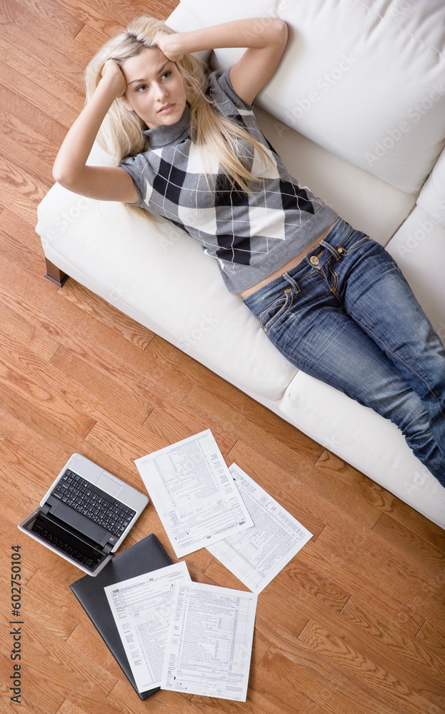 Obraz premium High angle view of a young woman frustrated while doing paperwork. Vertical shot.
