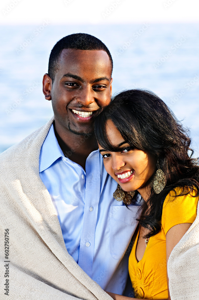 Young romantic sharing a blanket by the ocean Young romantic sharing a blanket by the ocean