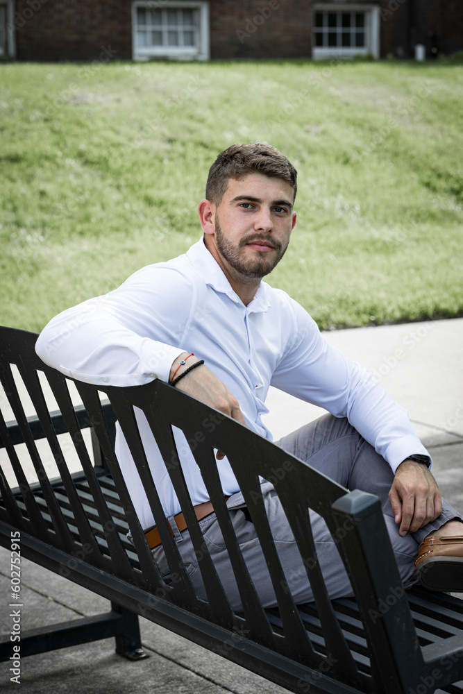 Fototapeta premium Young man sitting on a bench looking backward at the camera