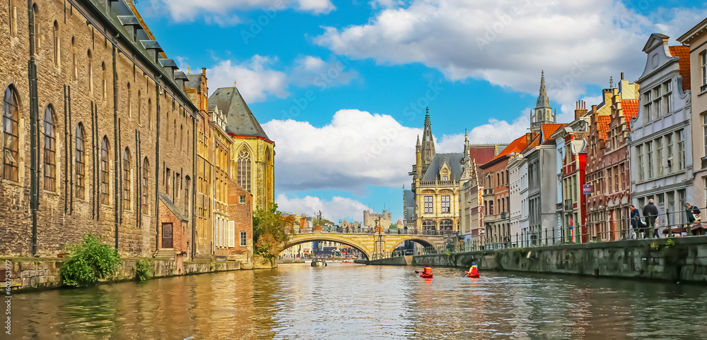 Gent, Belgium - October 9. 2021: River cruise sightseeing on beautiful belgian city river Leie, medieval gothic church, St. Michaels stone arch bridge on sunny summer day