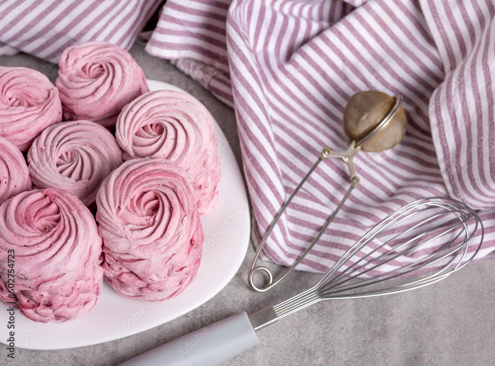 Fototapeta premium tasty delicious homemade zephyr pink marshmallows with blackberries taste.sweet dessert in box,on kitchen towel,gray tiles surface.whisk tea strainer accessories,sugar powder.pattern close up texture