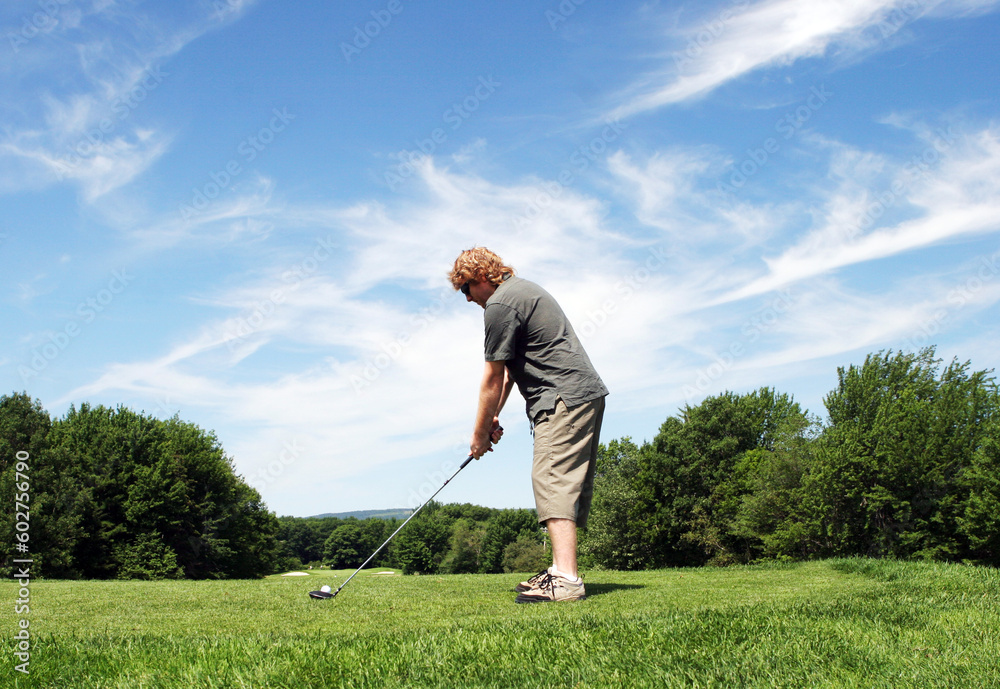 Man prepares to hit a golf ball on the course. Man prepares to hit a golf ball on the course.