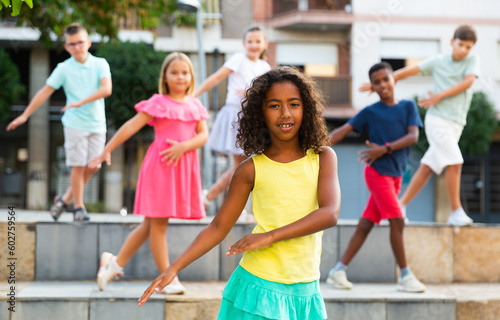 Young boys and girls dancing outdoors. They're performing street dance moves and having fun. © JackF