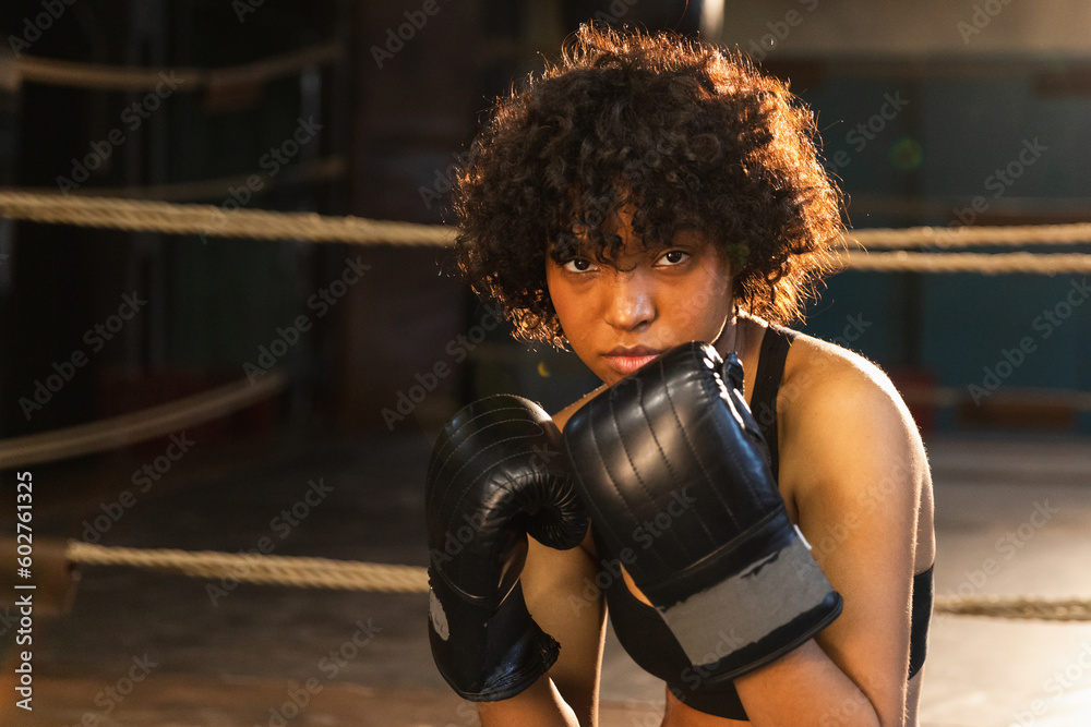 Outcry independent girl power. Angry african american woman fighter with boxing gloves looking serious aggressive standing on boxing ring. Strong powerful fighter girl training punches - obrazy, fototapety, plakaty 