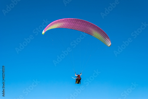 Two people (Instructor with student) flying with a paraglider above Sopelana beach near Bilbao (Basque Country). There are no other objects or people in the photo taken with a telephoto lens.