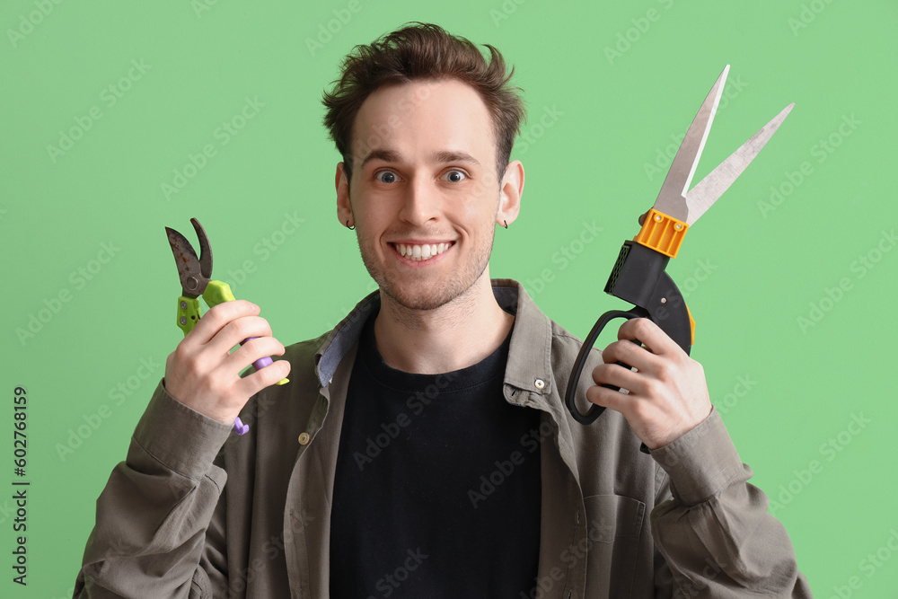 Young man with secateurs on green background Young man with secateurs on green background